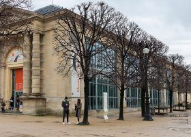 Exterior of Musee l'orangerie with people and a row of trees